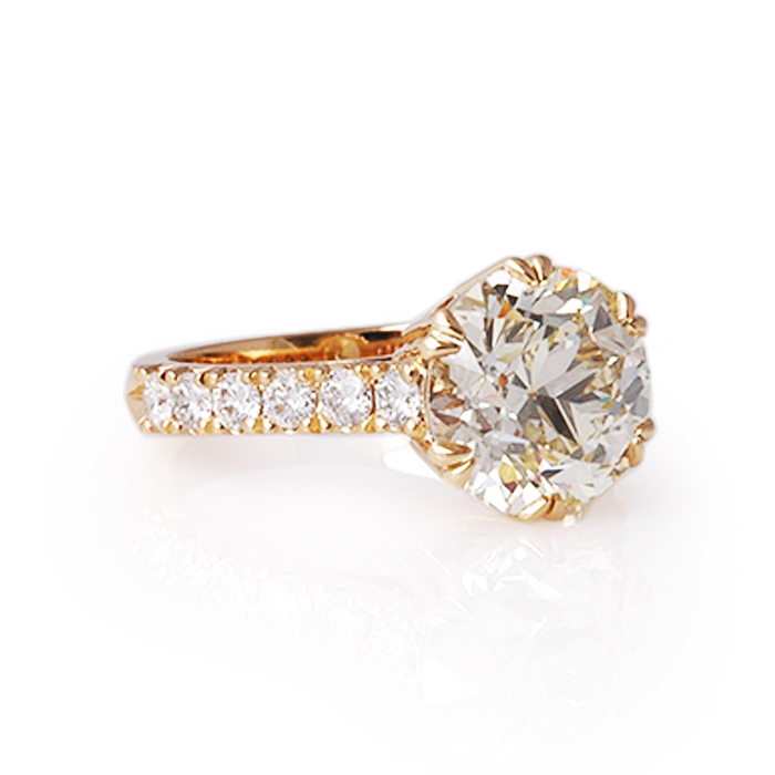 geelgouden solitair ring met zeer grote diamant en kleinere diamanten op de scheen.